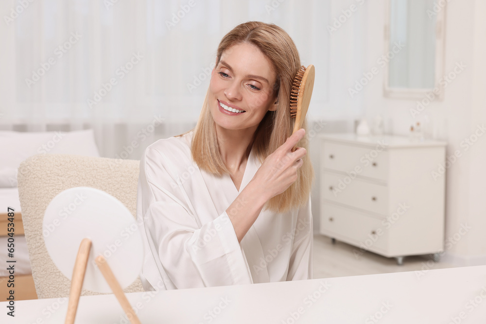 Wall mural beautiful woman brushing her hair at vanity in bedroom