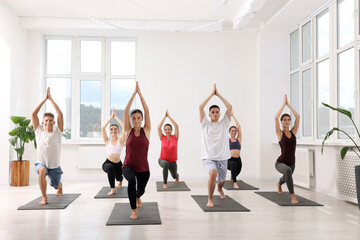 Group of people practicing yoga on mats indoors