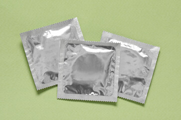 Condom packages on light green background, flat lay. Safe sex
