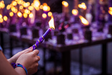 Hand of an unknown person holding a candle with his hand for the festival of the Lord of Miracles in Lima, Peru - obrazy, fototapety, plakaty