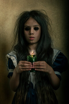Una ni&ntilde;a fantasma de cabello largo y vestido con una vela encendida en las manos