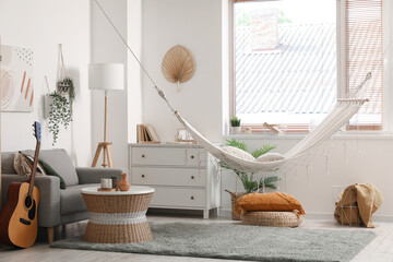 Interior of stylish living room with hammock, grey sofa and coffee table