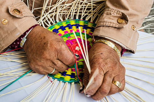 Close-up of female hands weaving a placemat from Paja Toquilla Straw. The straw handicraft is a popular souvenir from Ecuador.