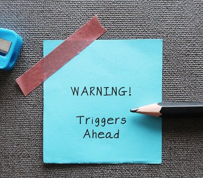 Blue stick note with handwritten text WARNING! triggers ahead - concept of knowing your triggers, to aware or identify emotion triggers when encountering something difficult