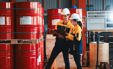 Two factory workers or inventory inspector conduct professional inspection on hazardous chemical barrels in warehouse, chemistry storage workplace and industrial profession concept. Exemplifying