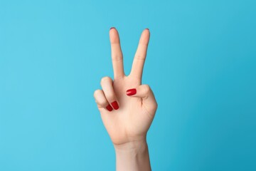 This photo features a woman's hand, adorned with red manicure, confidently displaying a victory sign against a blue background. A moment of self-assuredness!

 Generative AI