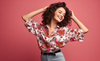 Fototapeta premium Young cheerful woman wearing a floral patterned shirt and jeans dancing over a pink background