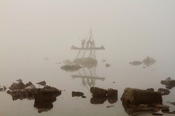 Statue of a boat with rowers in the fog on a pond