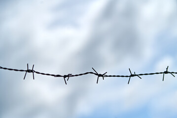 Silhouette single barbed wire protects property or defense with the dull sky background.