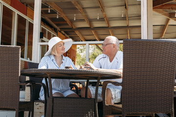 Fototapeta na wymiar Happy mature middle aged couple talking, woman showing off her hat, flirting.