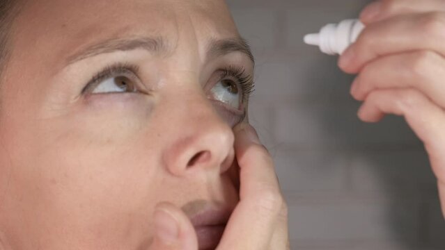 Female drip drops into the eye. A sick female drip drops into her eyes because of health problems.