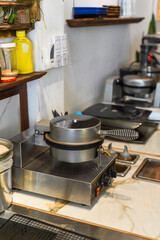 Waffle iron machine on the table in cafe kitchen
