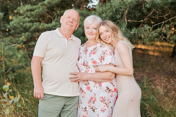 Happy family with elderly mother, father and daughter hug each other and smiling in the park