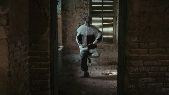 Long zoom out shot of scary clown having creepy dance inside forsaken building
