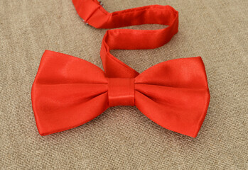 Stylish red bow tie on natural linen texture.