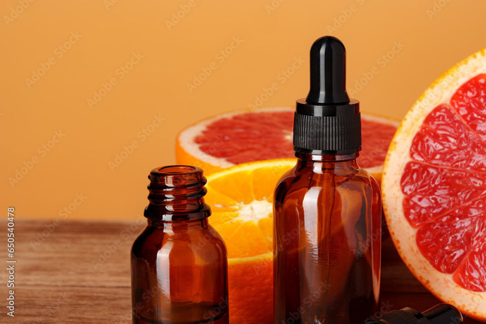 Wall mural Glass bottle with essential citrus oil on orange background