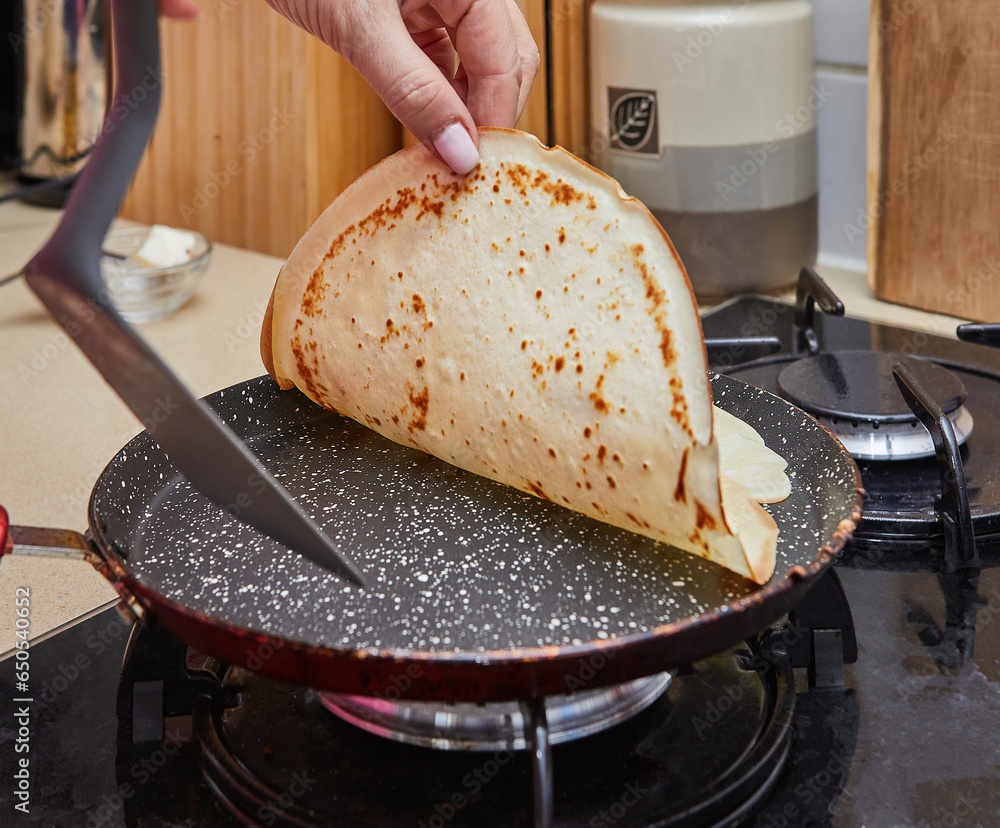 Poster Cooking Crepe Suzette pancakes in frying pan on gas stove