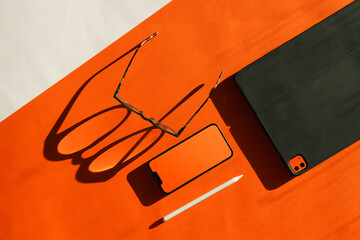 Electronic device blank screen mockup. Orange color. Smart phone and graphic tablet. Glasses shadow.