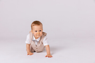 Happy baby. Little boy in a white shirt and bow tie crawling on a white background. Children portrait. Stylish man in fashionable a bow-tie.