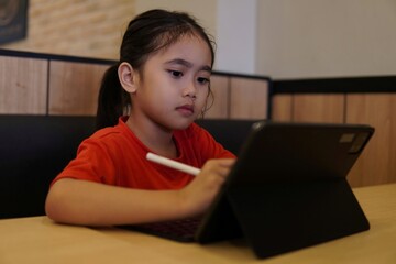 Selective focus image of young Asian girl drawing on digital tablet. Technology concept