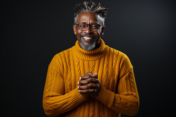 Touching scene of a content elderly man in cozy sweater, eyes shut with clasped hands evoking gratitude and warmth, against simple background.