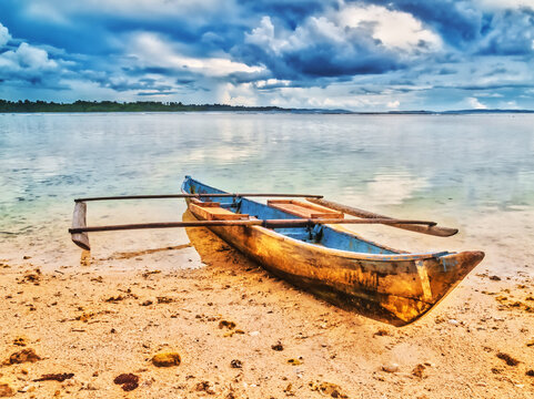 Old wooden fishing canoe anchored on a sandy beach