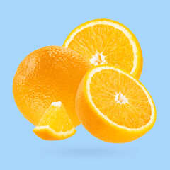 Juicy oranges closeup fly as art composition. Whole, half and piece fruits on pastel blue...