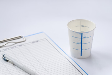尿検査の紙コップと検査データの記録イメージ。健康診断、看護記録