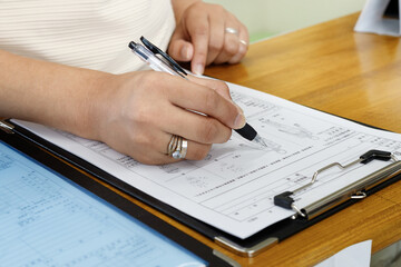 記入する女性の手元。申し込み、契約、問診