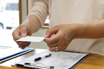 受付で診察券、カードを提示する女性の手元。