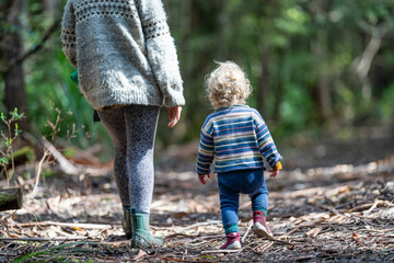 Mother with baby in a carrier on her chest on a hike, taking a bush walk in Summer in a national...
