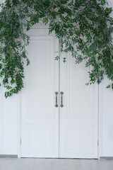 White classic door with branches of greenery on top in the interior