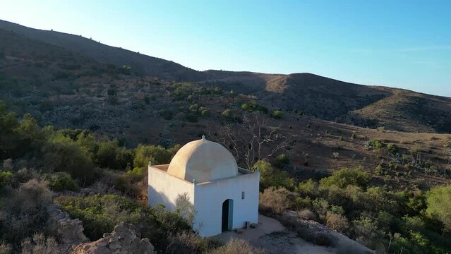 Sunset's golden embrace over a saint's tomb, seen from above, where the righteous find eternal rest and peace