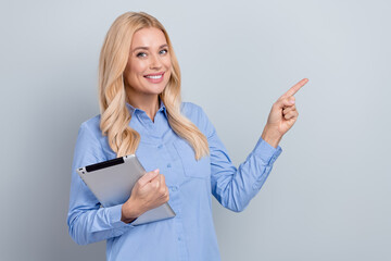 Photo of attractive positive executive director lady hold tablet indicate finger empty space isolated on grey color background