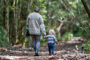 Mother with baby in a carrier on her chest on a hike, taking a bush walk in Summer in a national park in Sydney, nsw, Australia