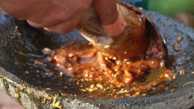 A footage of peanut sauce is being made in traditional way. Dressing of Indonesian fruit salad called rujak