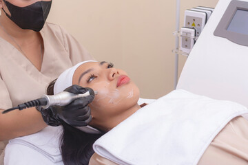 Obraz na płótnie Canvas Using an RF electromagnetic device for radiofrequency skin tightening or contouring treatment. At a facial care, dermatologist or aesthetic clinic.