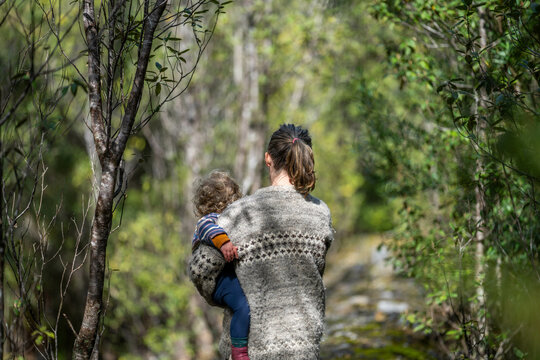 Mother with baby in a carrier on her chest on a hike, taking a bush walk in Summer in a national park in Sydney, nsw, Australia