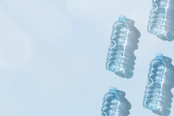 Minimal Pattern Plastic bottles water at sunlight with shadow on blue, aesthetic top view. Distilled drinking water. Pollution, environmental protection. Eco trend to reduce disposable plastics
