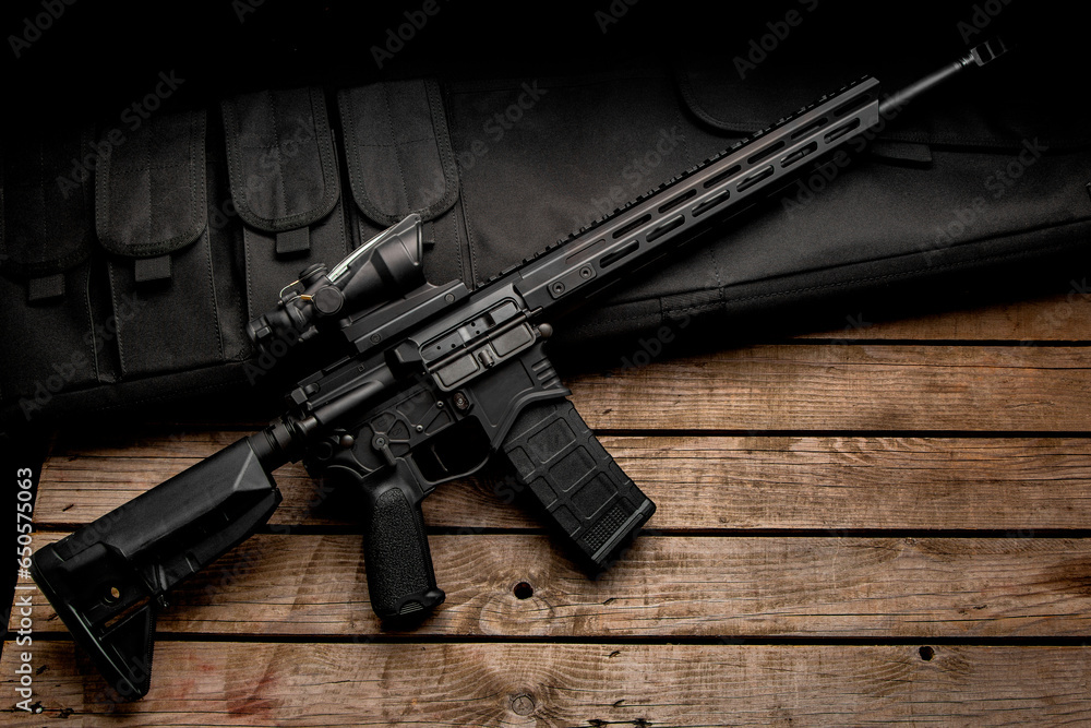 Poster Modern automatic rifle on a wooden background. Weapons for police, special forces and the army. A carbine with red dot sight on a dark back