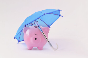 Piggy bank under blue umbrella - Concept of money protection and financial security