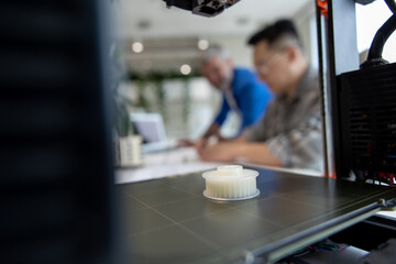 Two men architects using 3D printer in office and projecting house, drawing blueprints.