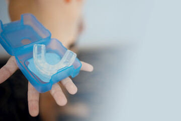 transparent mouth guard made of silicone, for straightening teeth in children, in a girl's hand, in daylight. Hygiene, dental care, occlusion correction, new technologies
