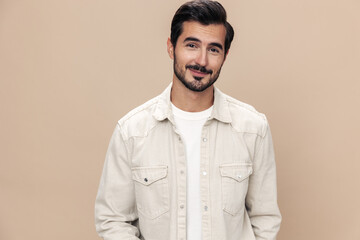 Obraz premium Portrait of a stylish male fashion model on a beige background in a white t-shirt looks at the camera, trendy clothing style, copy space, space for text