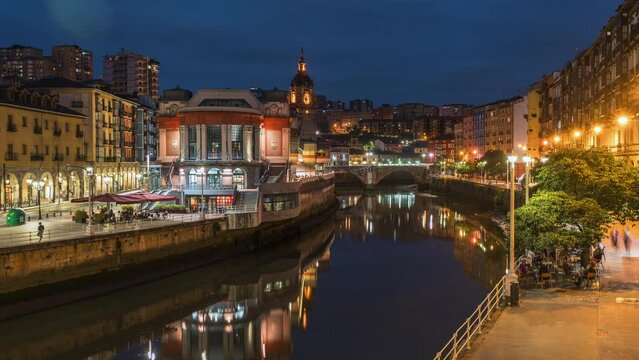 Dusk to night timelapse view of Bilbao cityscape including the historic La Ribera food market in Bilbao, Basque Country, Spain, zoom in.