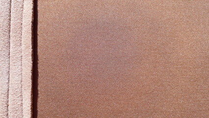 Beige background. Knitted beige fabric in a caramel shade. Fabric texture. Polyester.