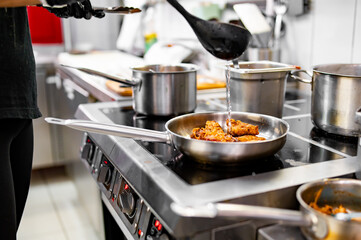 chef cooking chicken wings in a sauce on pan in the kitchen