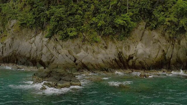 Ocean waves crash peacefully across banded tropical rocks of Looc beach sirigao
