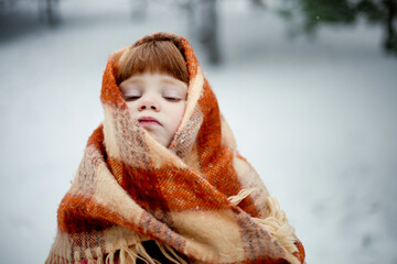 little red-haired girl wrapped in a scarf in winter