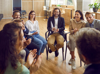 Group of business people sitting in a circle and talking discussing job and work projects in a...